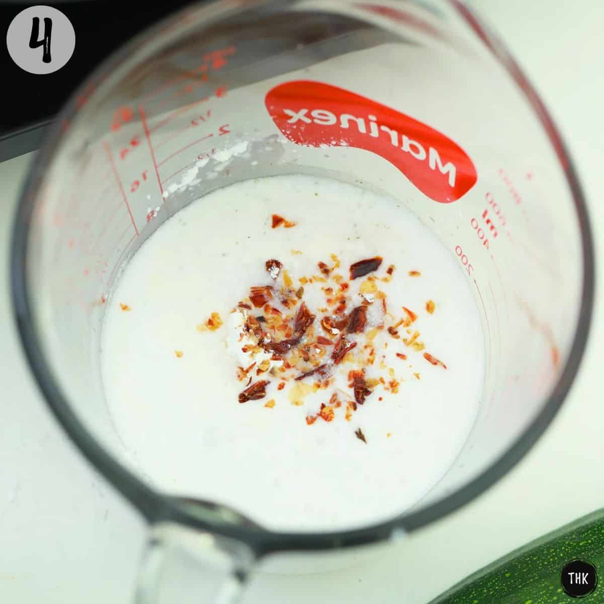 Milk, broth, wine and chilli flakes in measuring cup.