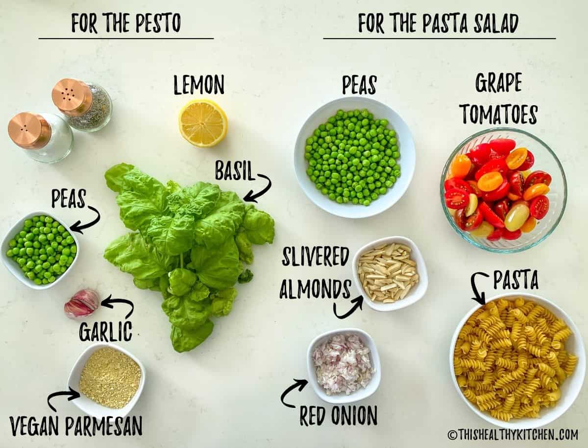 Ingredients to make pesto pasta salad scattered on white kitchen counter top.