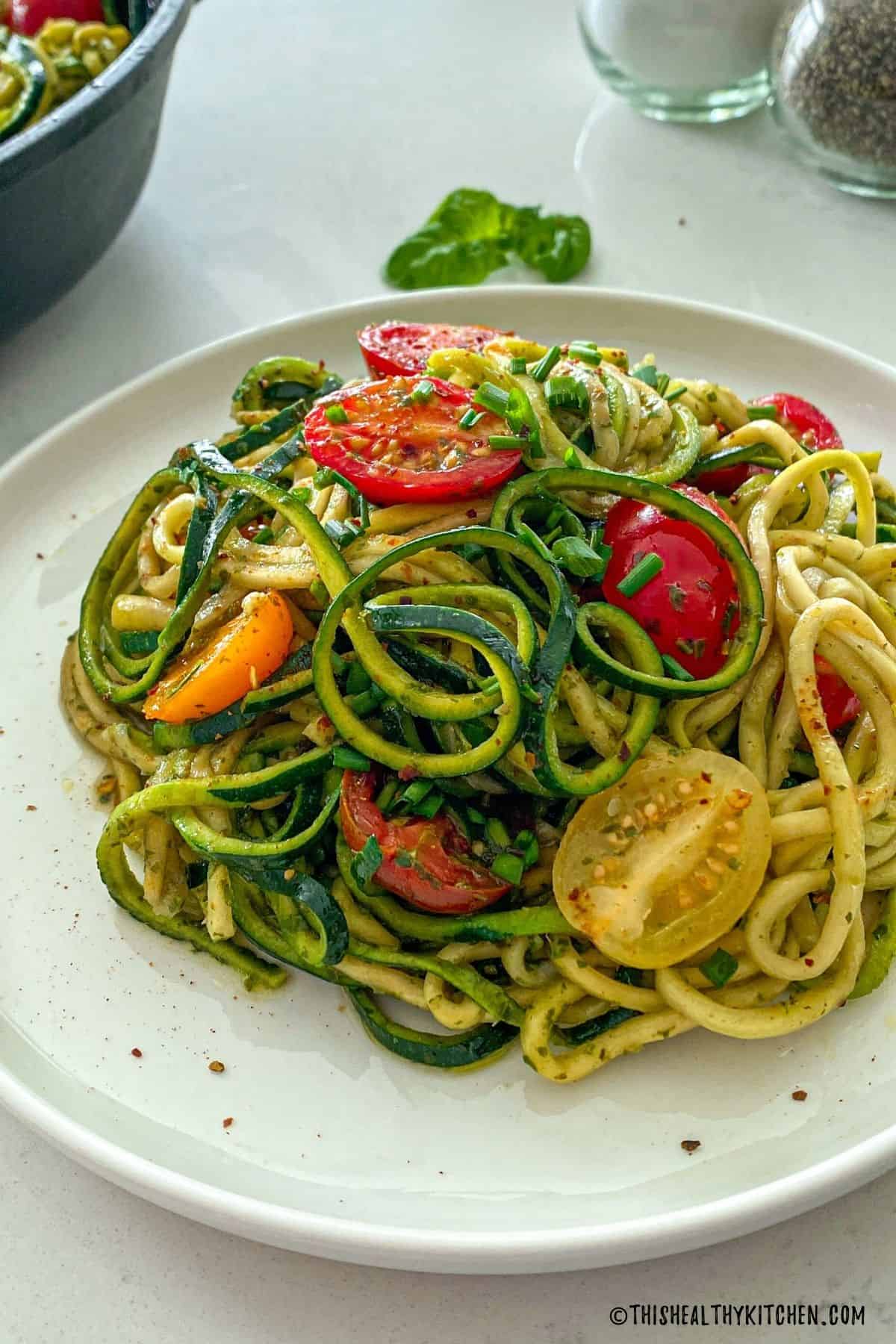 Side view of plate with spiralized zucchini noodles and cherry tomatoes.