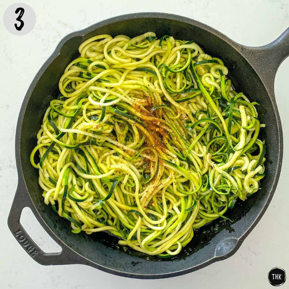 Cast iron pan with zucchini noodles inside.