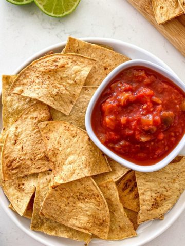 White platter with tortilla chips and bowl of salsa.