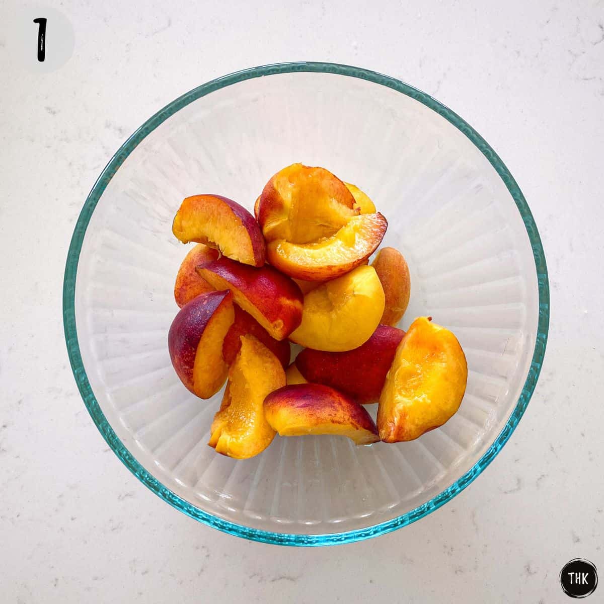 Sliced peaches in glass bowl.
