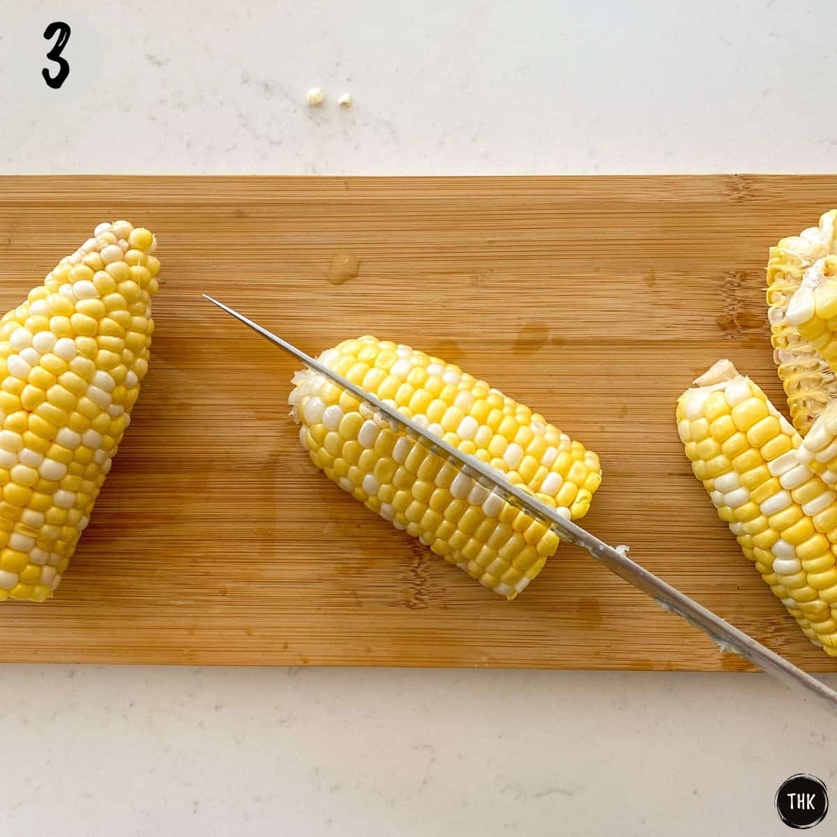 Knife cutting corn into corn quarters.