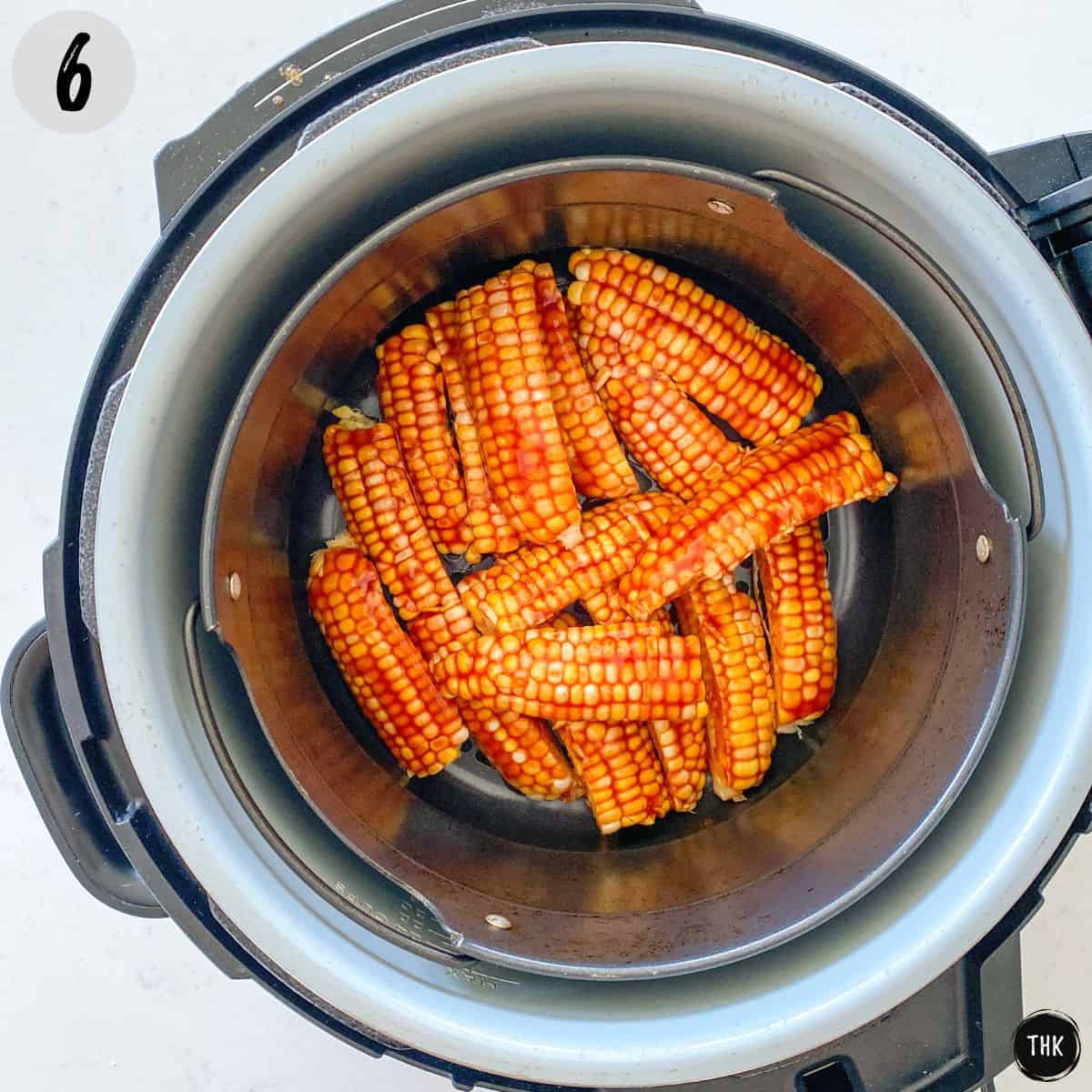 Corn pieces covered in bbq sauce sitting in air fryer basket.
