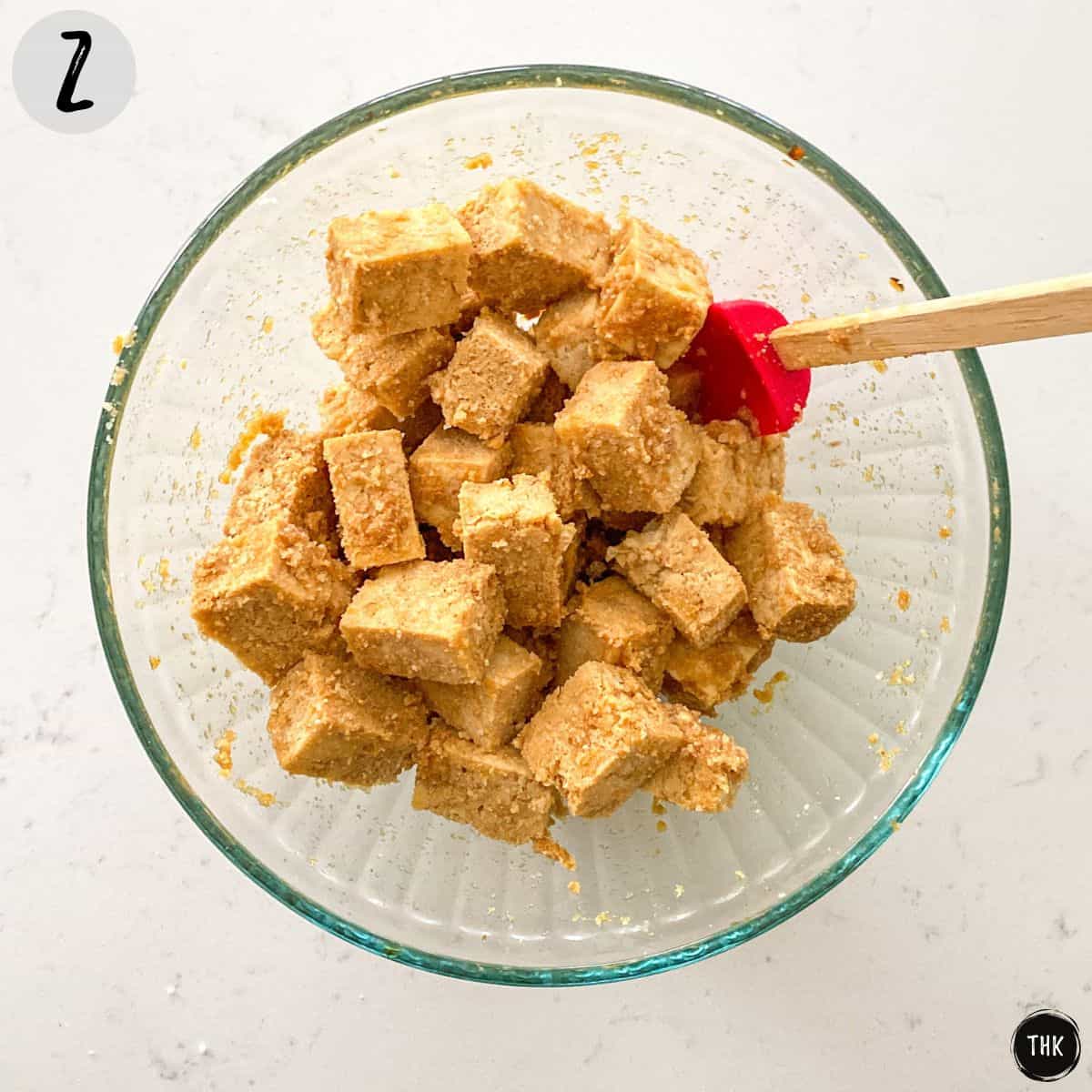 Tofu cubes in glass bowl with soy sauce and seasoning.