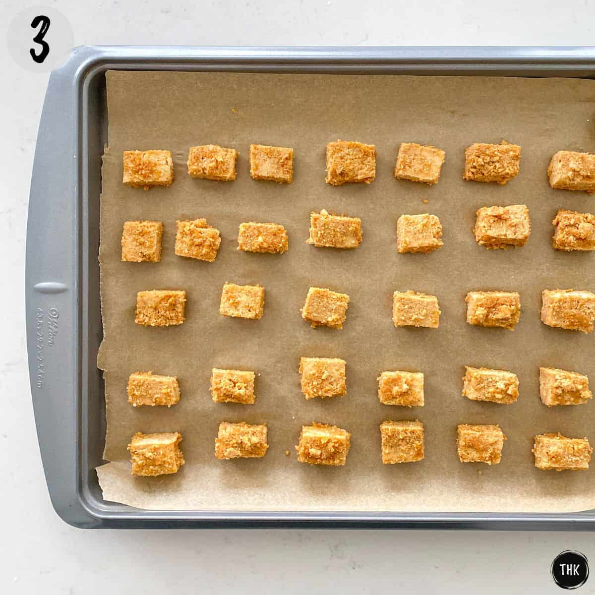 Tofu cubes on baking sheet lined with parchment paper before baking.