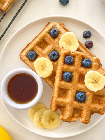 Plate with two waffles, with banana slices and blueberries on top.