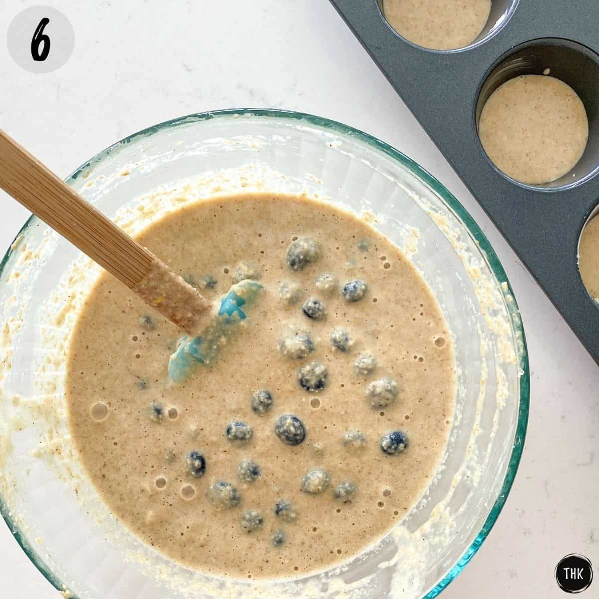 Mixing bowl with blueberry muffin batter inside.