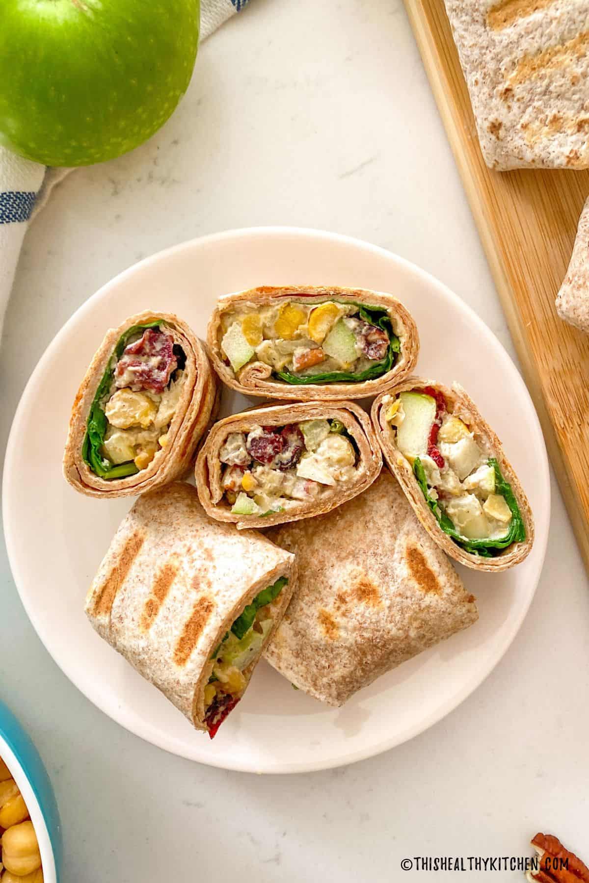 Vegan chicken wraps cut into pinwheels arranged cut side up on a white plate.