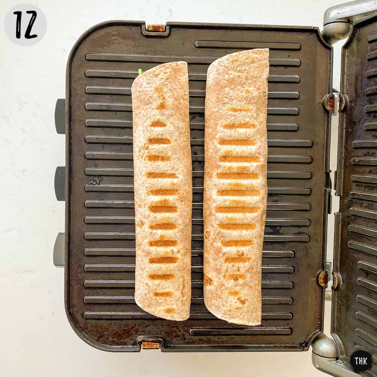Two tortilla rolls on panini press with grill lines on them.
