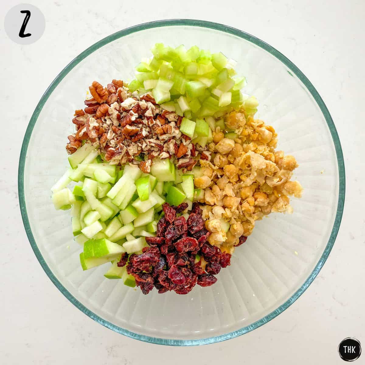 Large bowl with chickpeas, cranberries, diced apple, diced celery and chopped pecans.
