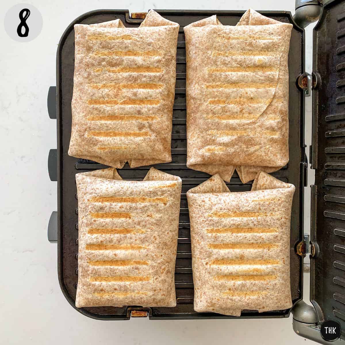 Four wraps with grill lines on panini press.
