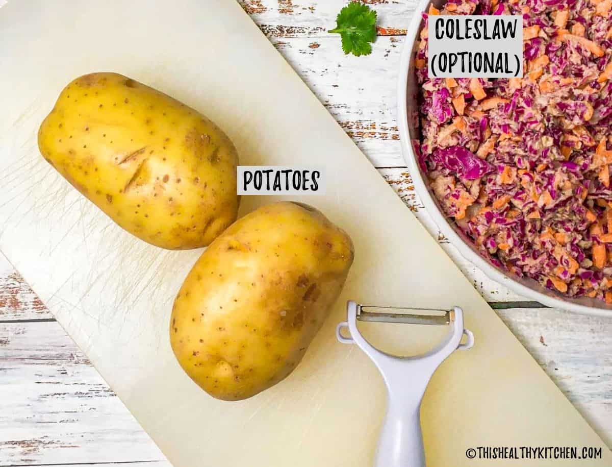 Potatoes on cutting board with bowl of coleslaw beside it.