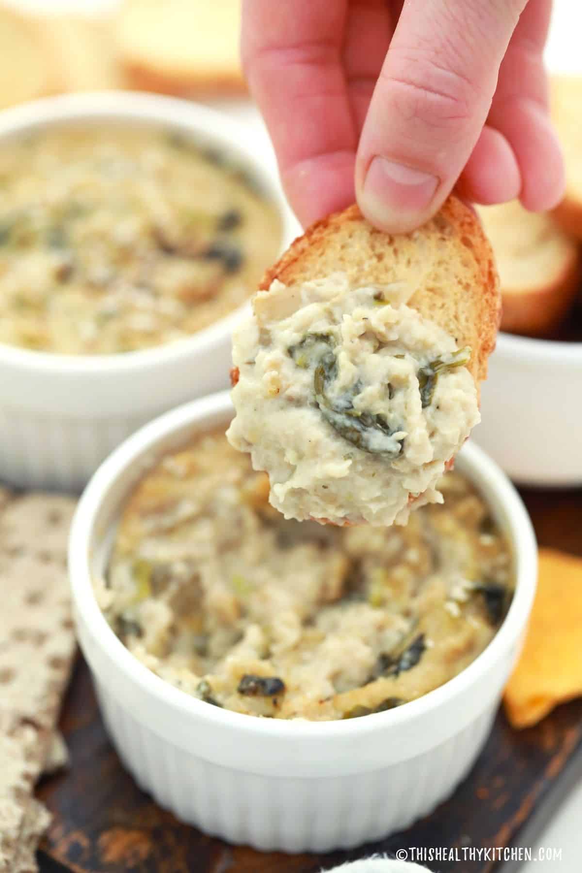 Crostini dipped in creamy white dip ribboned with spinach.