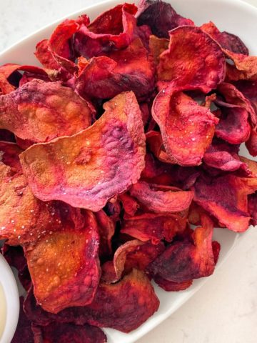 Close up of air fryer beet chips in white serving plate.