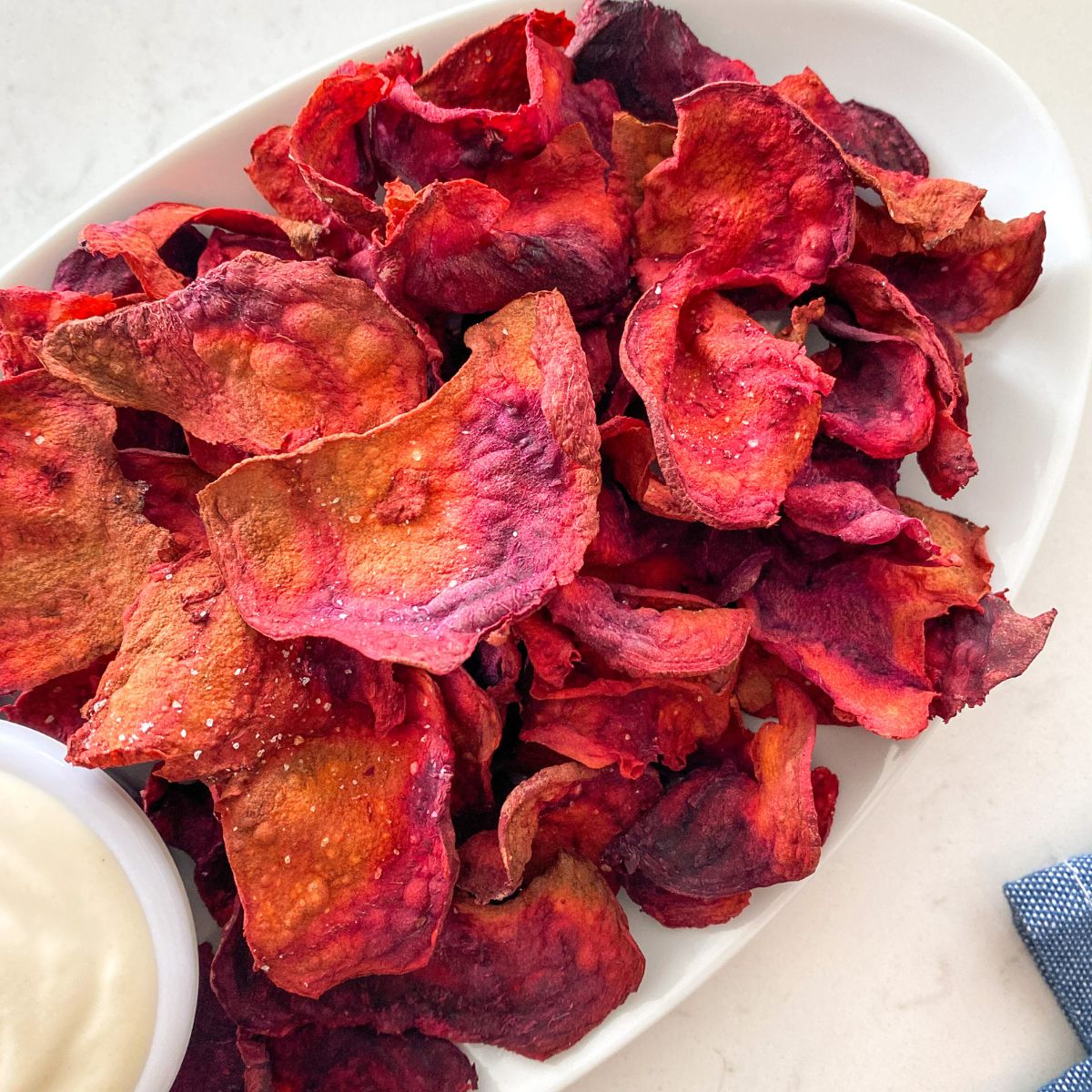 Close up of air fryer beet chips in white serving plate.