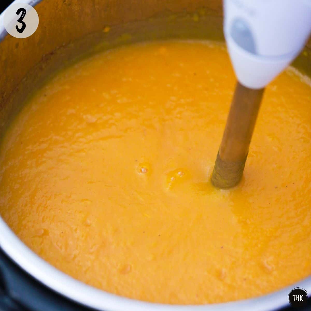 Immersion blender pureeing large pot of soup.