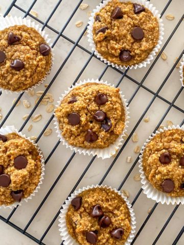 Muffins with chocolate chips and oats scattered around them.