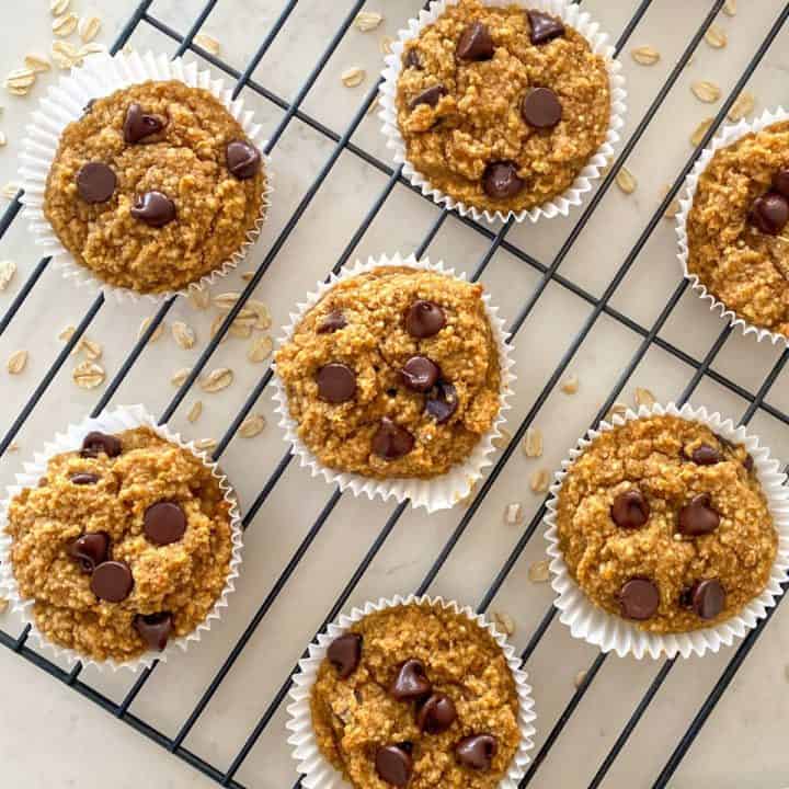 Muffins with chocolate chips and oats scattered around them.