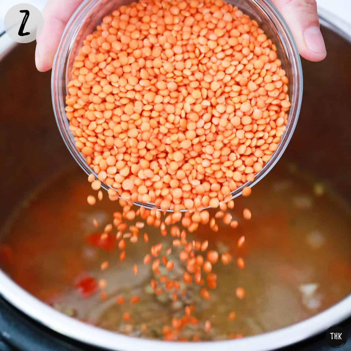 Red lentils being poured into pot.