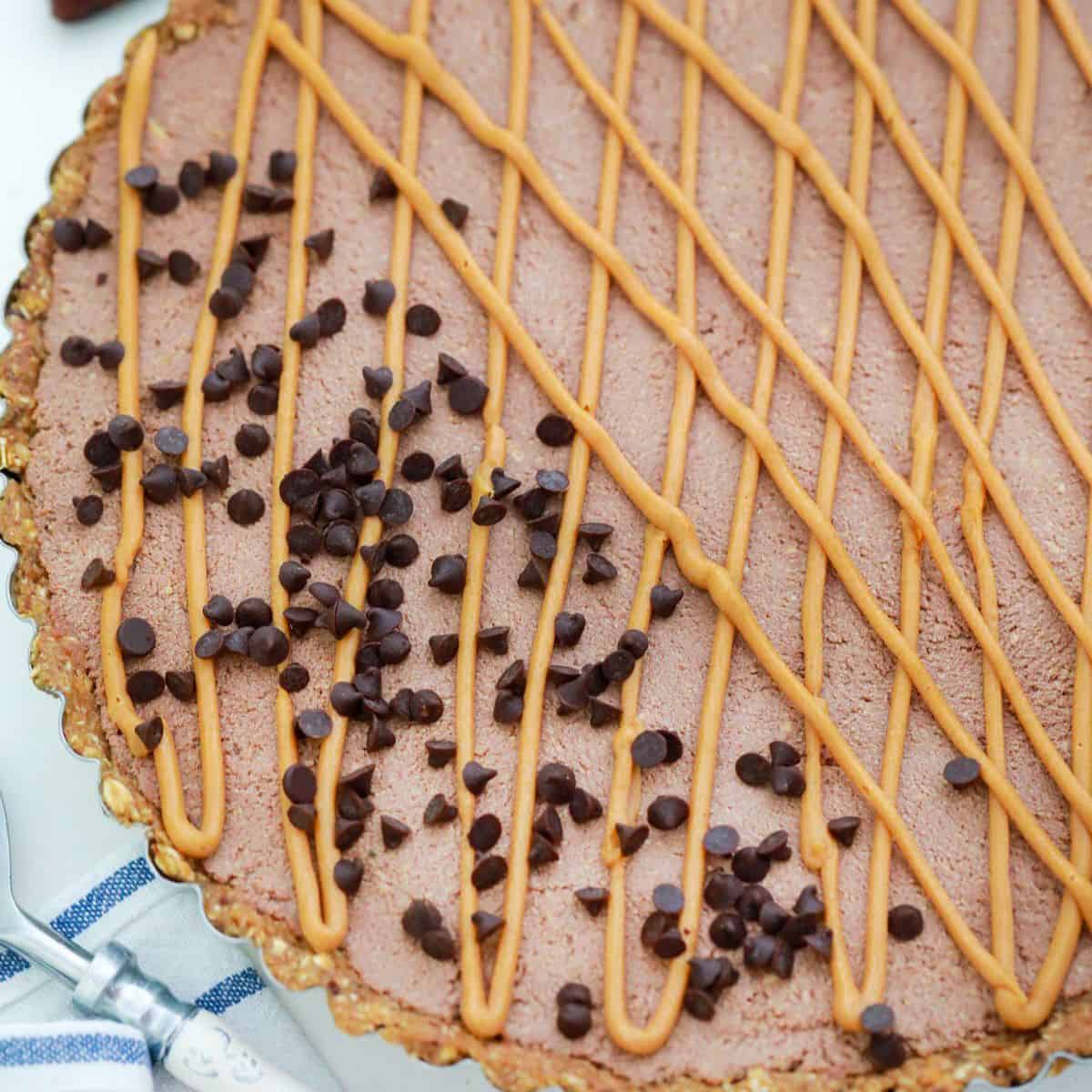 Peanut butter pie in tart pan with chocolate chips on top.