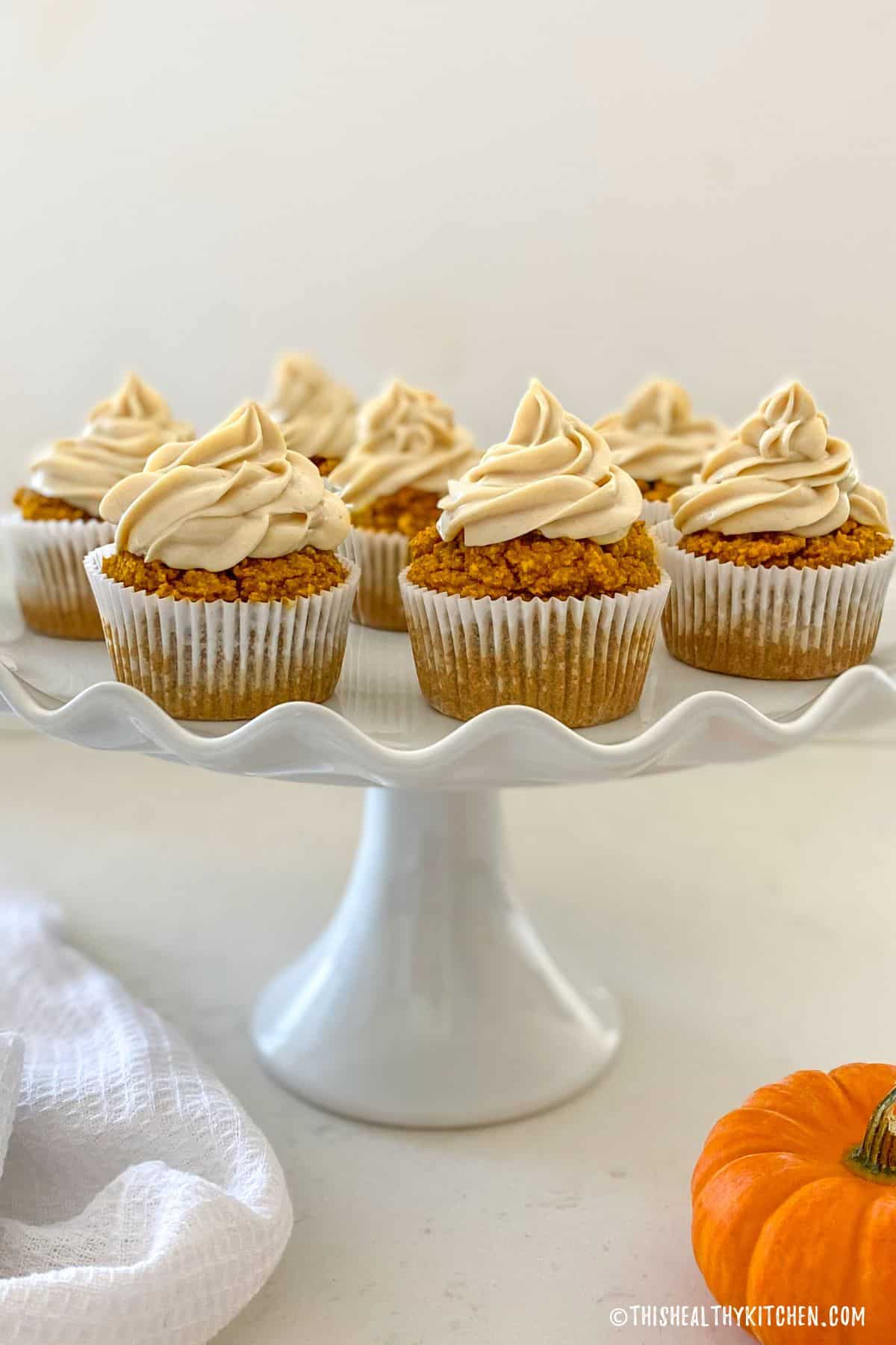 Side view of pumpkin cupcakes on cake plate.