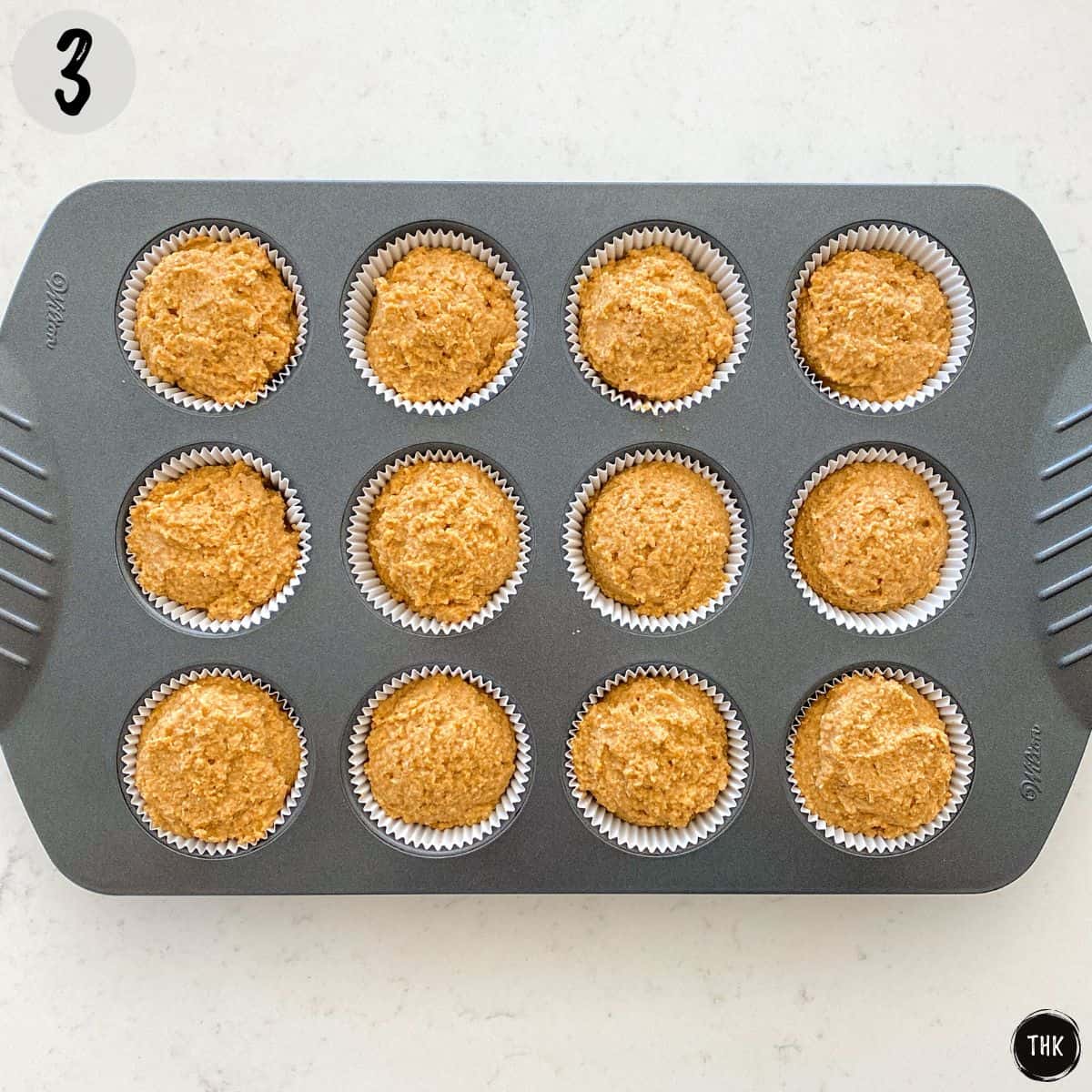 Pumpkin cupcake batter in muffin pan.