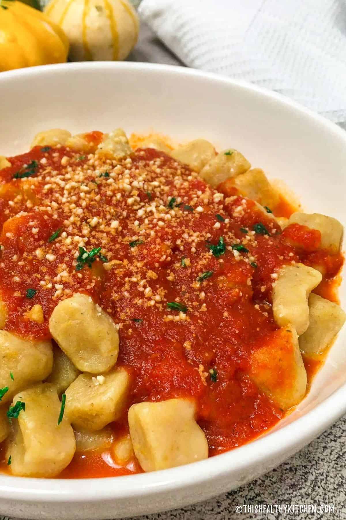 Bowl of gnocchi with tomato sauce on top.