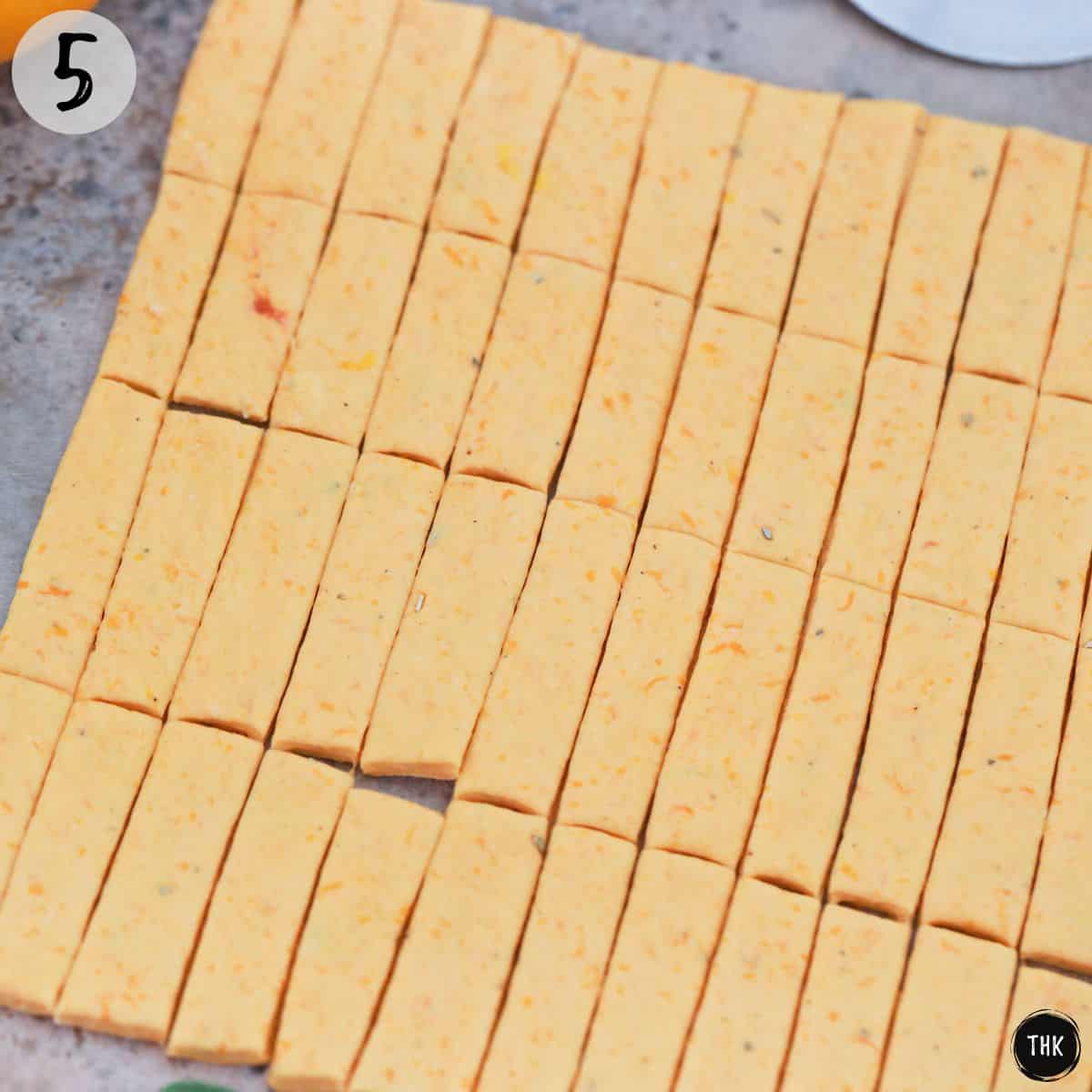 Orange coloured dough stretched and cut into grid pattern.