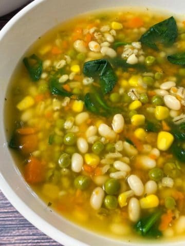 Bowl of vegetable barley and bean soup with spinach.