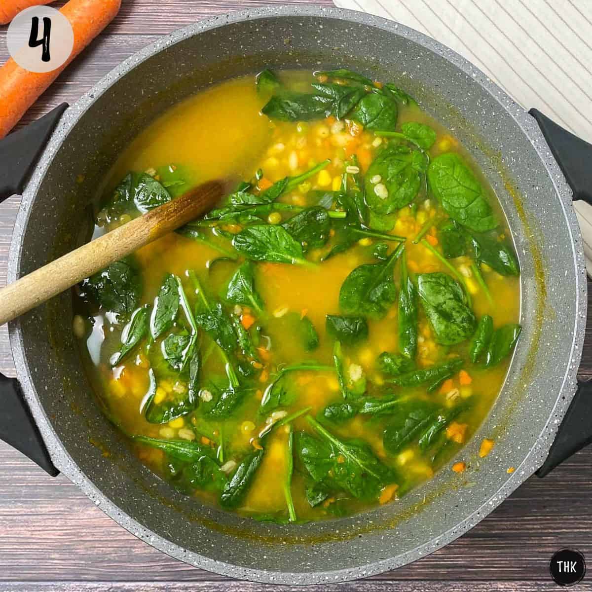 Pot of soup with wilted spinach inside.