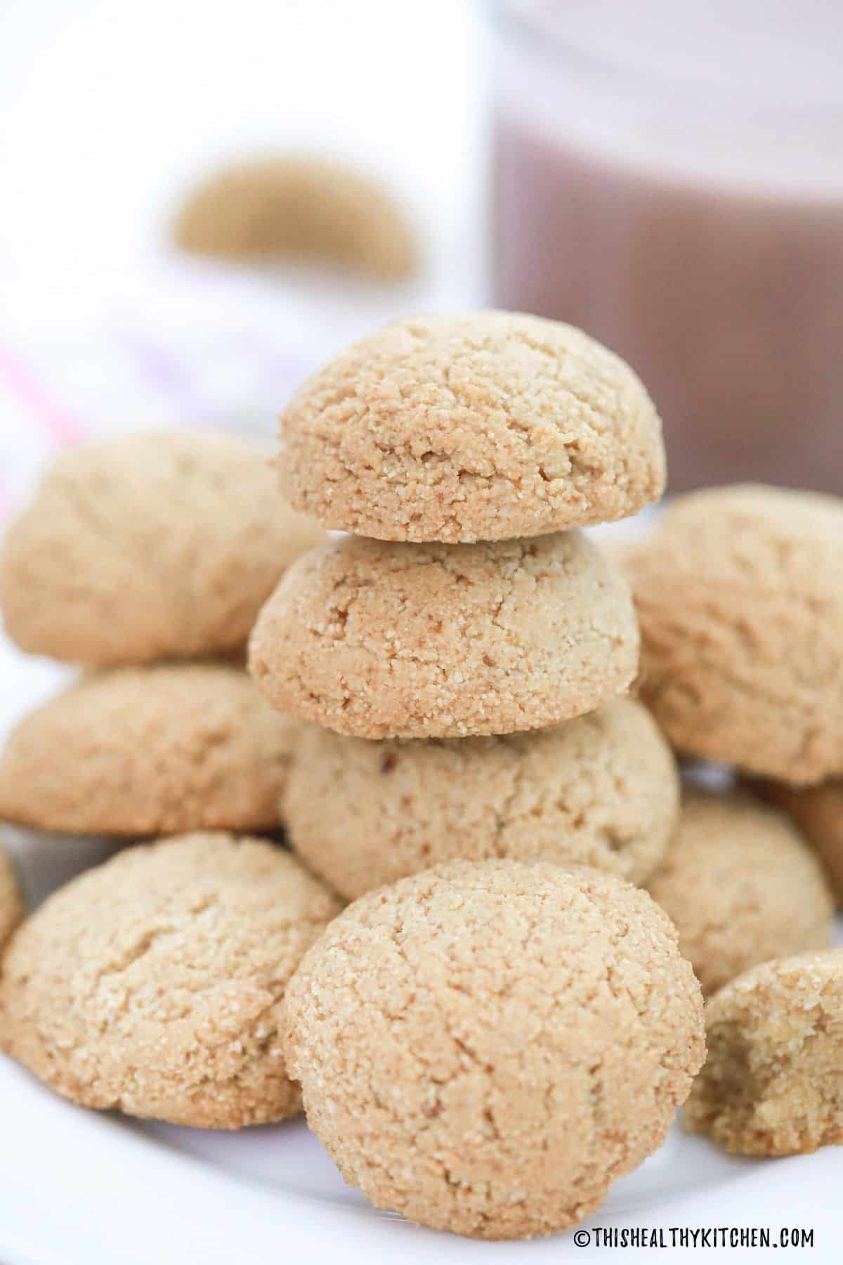 Almond flour cookies in a stack with more surrounding them.
