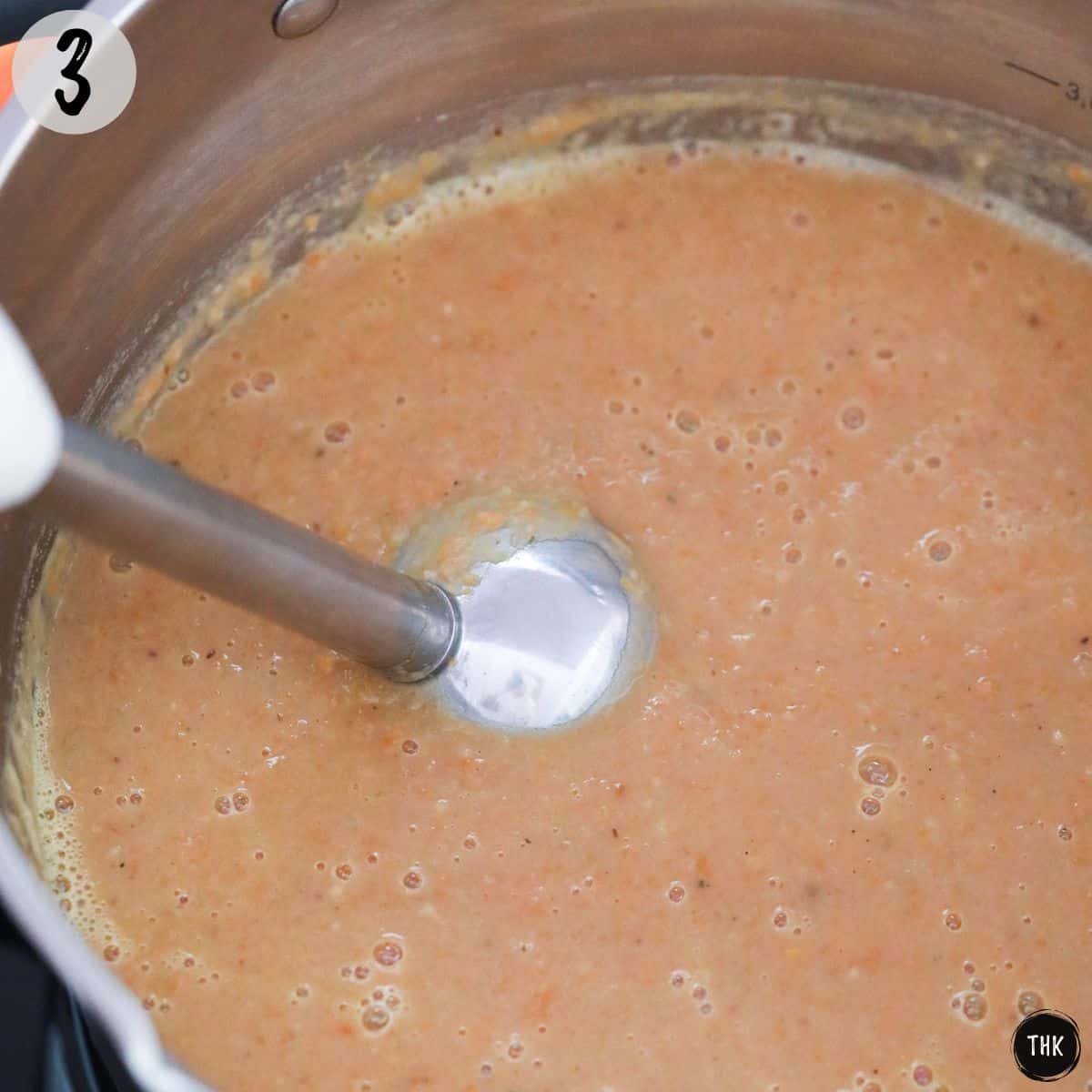 Hand blender pureeing pot of soup.