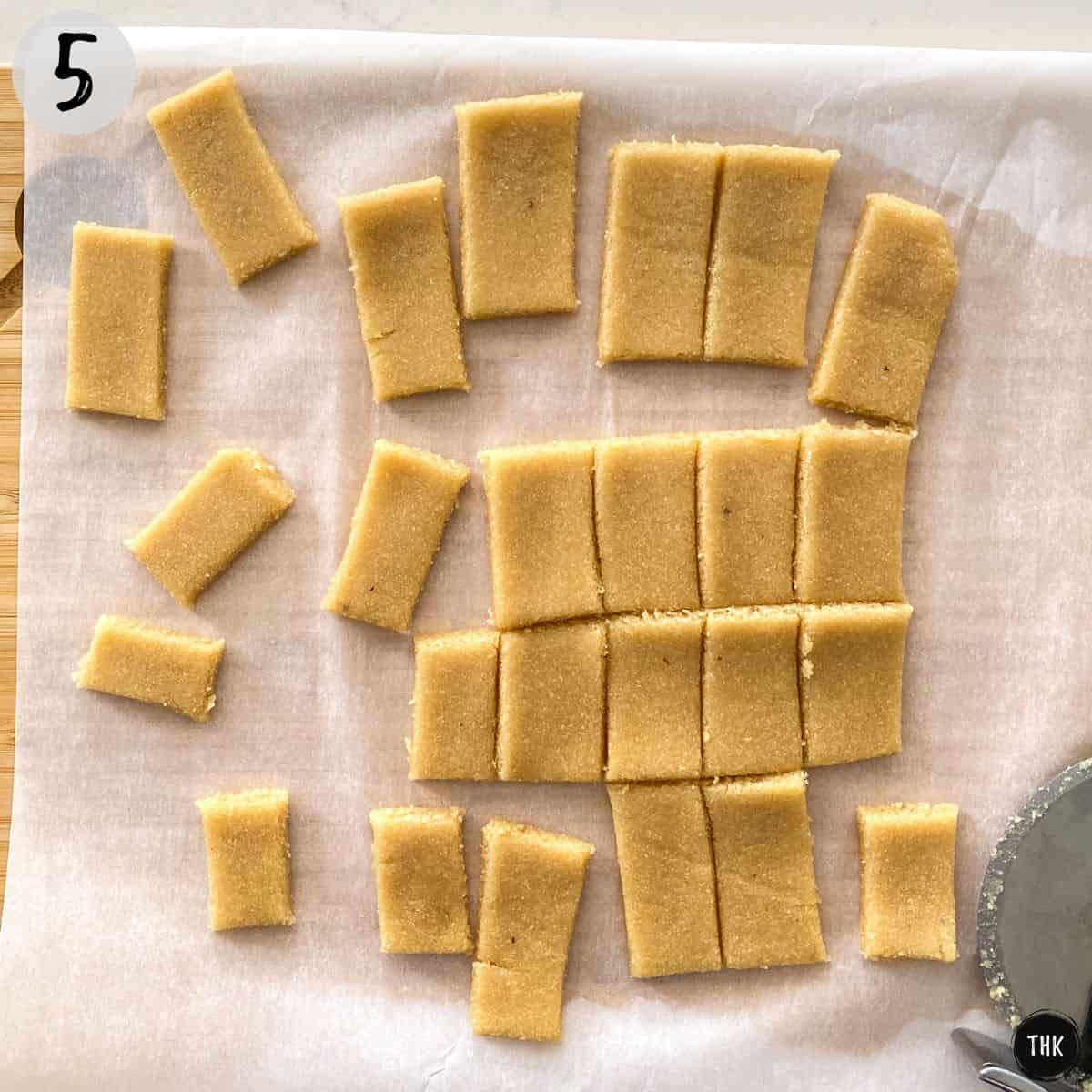 Rectangular cut outs of stretched dough with pizza cutter beside them.