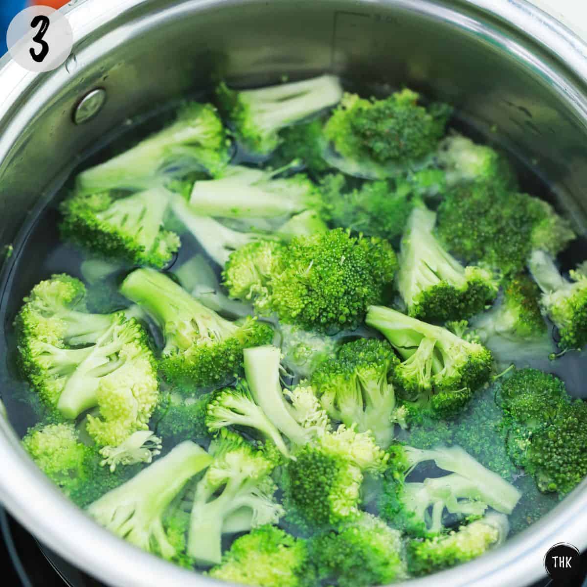 Broccoli florets in large pot of water.