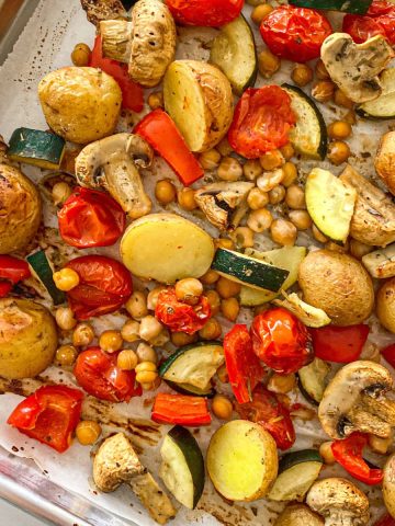Roasted potatoes, mushrooms, zucchini, chickpeas and peppers in baking tray.