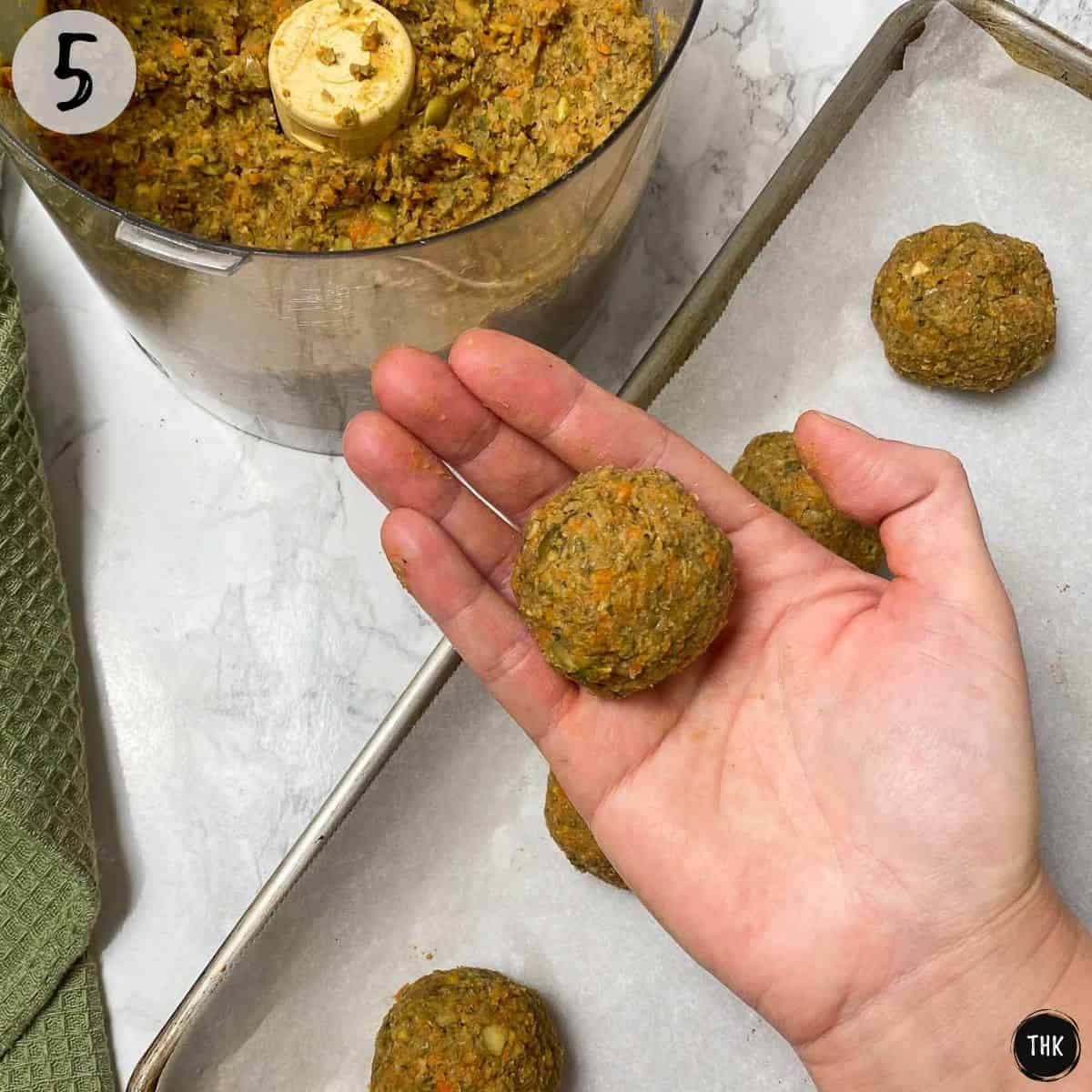 Hand holding up rolled uncooked vegan meatball.
