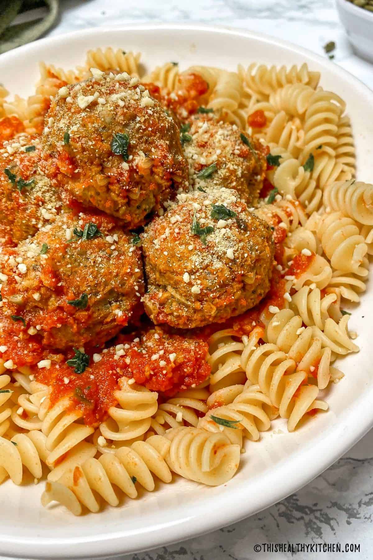 Plate of pasta with tomato sauce and meatballs on top.