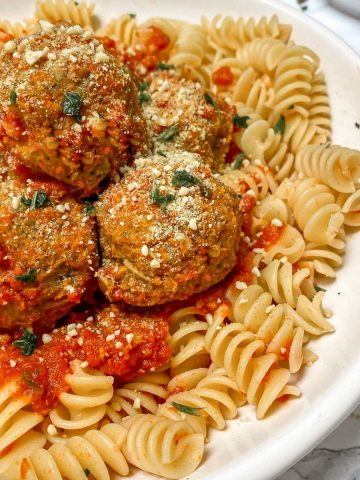Plate of pasta with vegan meatballs and tomato sauce on top.