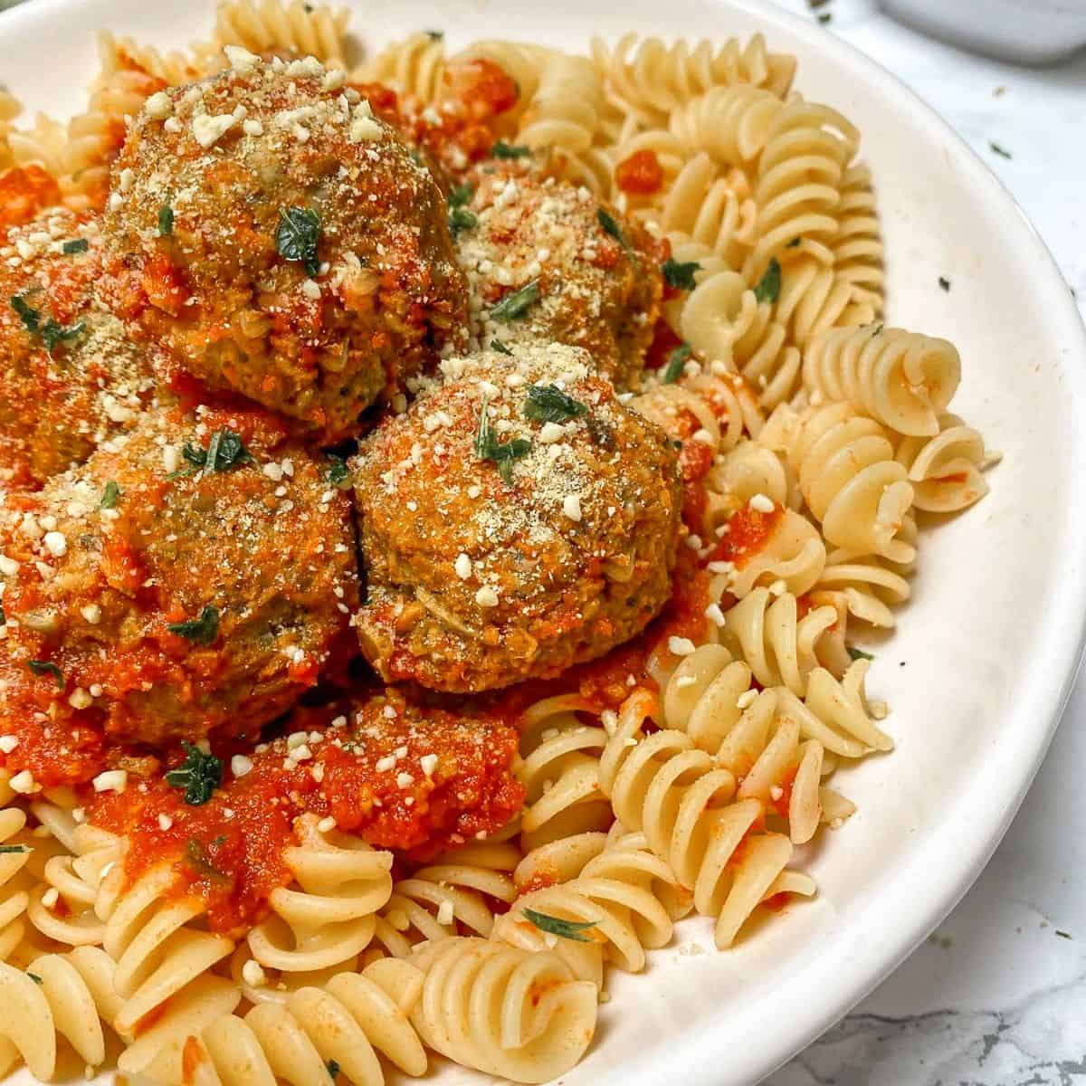 Plate of pasta with vegan meatballs and tomato sauce on top.
