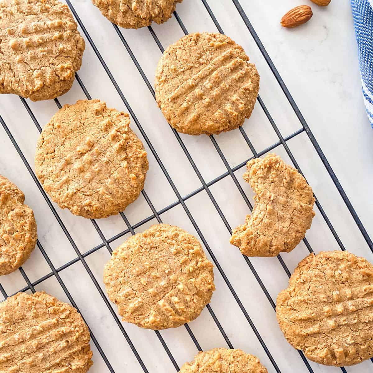 Almond butter cookies on cooling rack with bite taken from one.