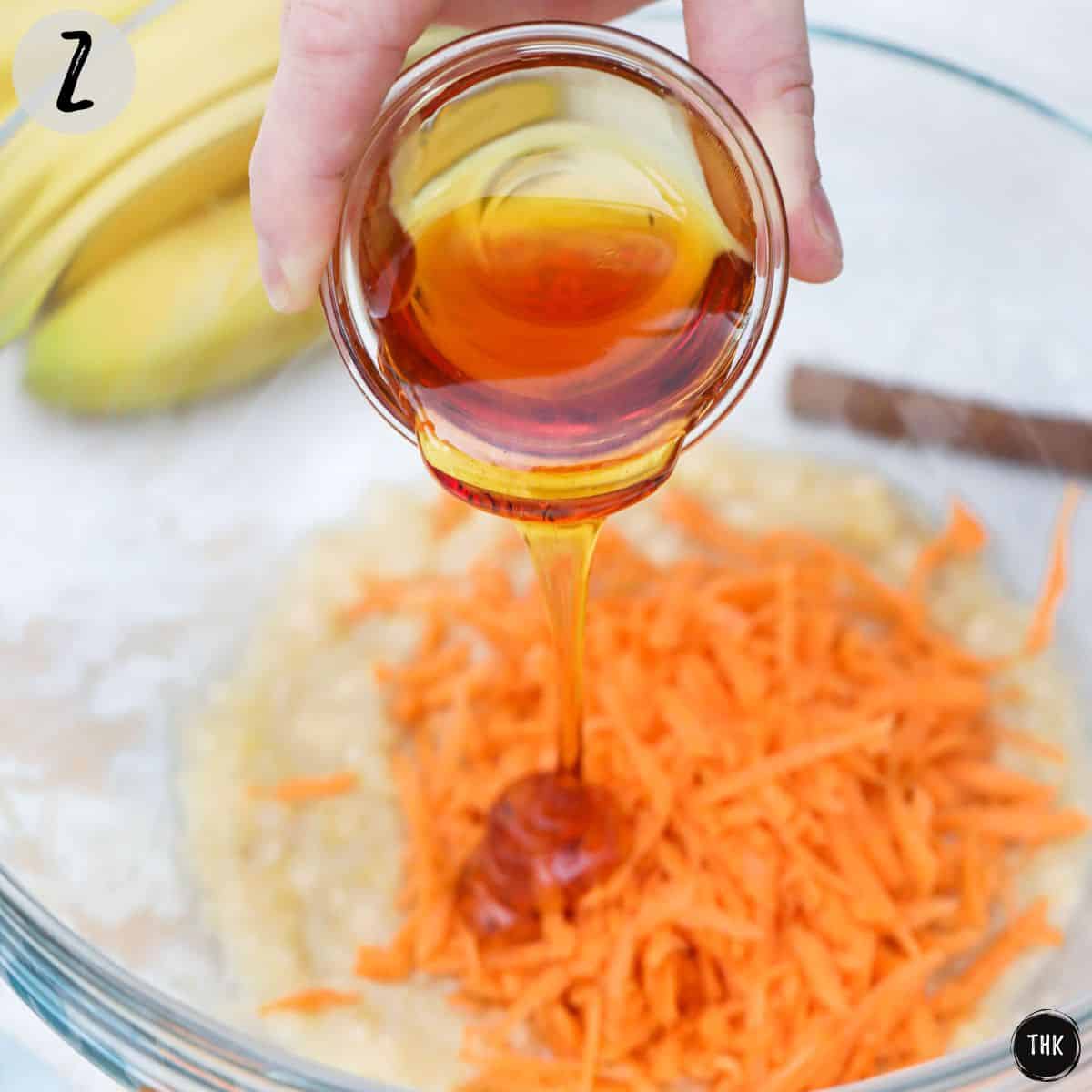 Maple syrup being poured into bowl with mashed banana and shredded carrot.