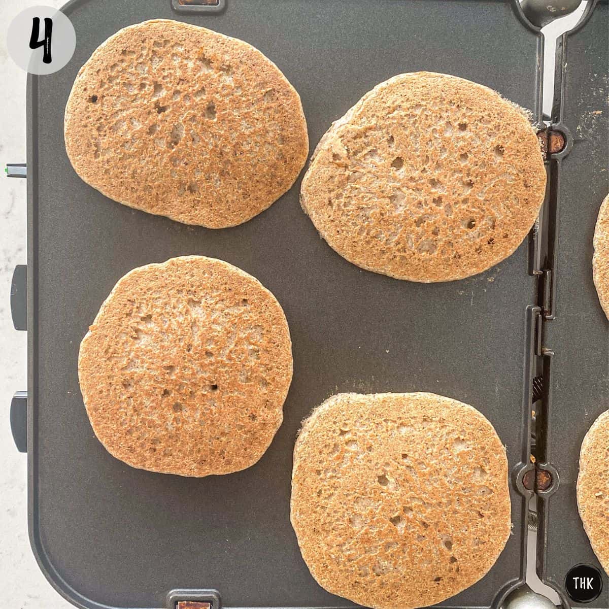 Pancakes being cooked on griddle.