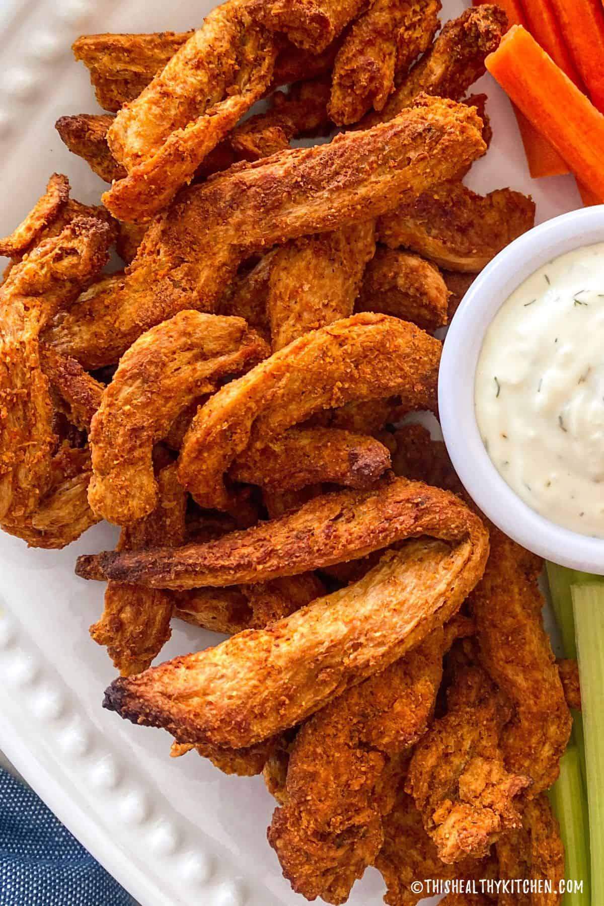Platter of buffalo soy curls with dipping bowl of ranch beside it.