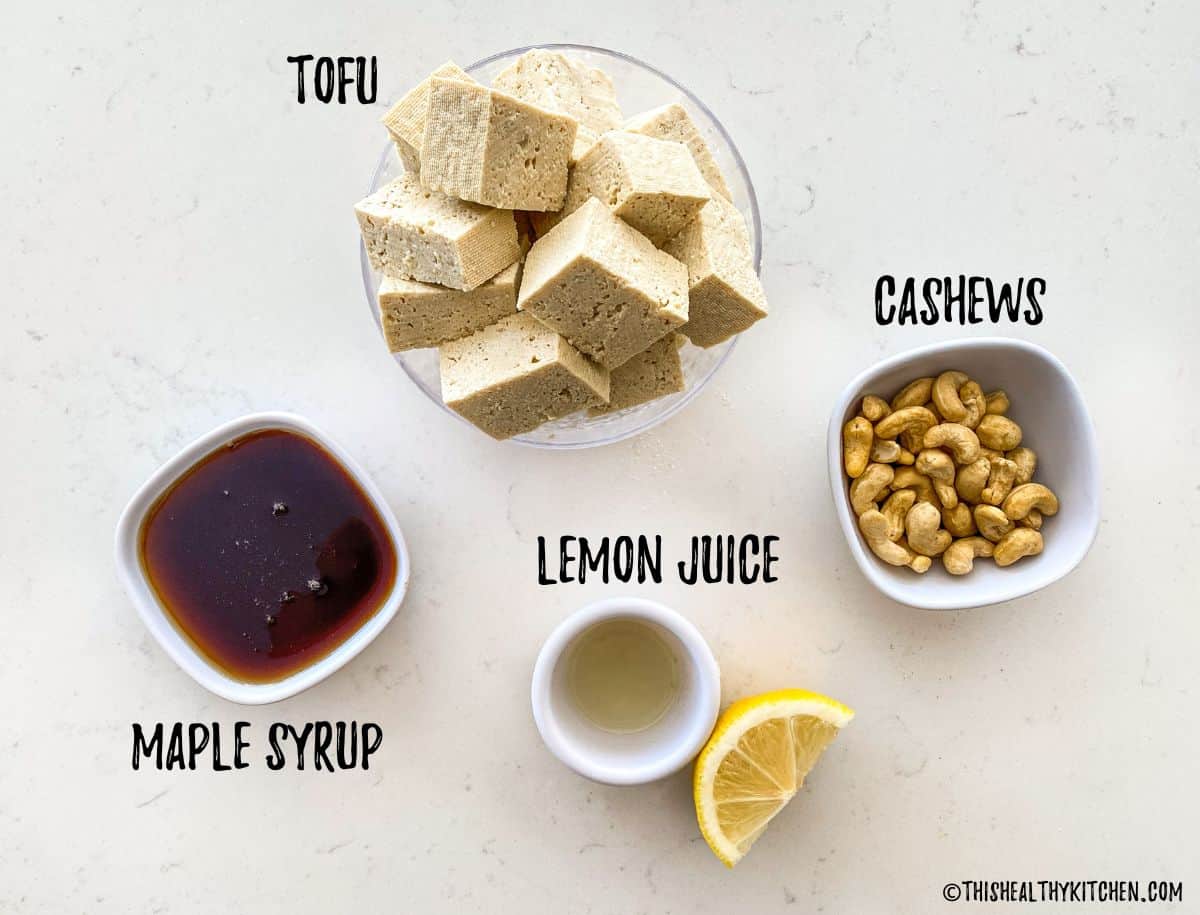 Bowl of tofu, cashews, lemon juice and maple syrup on kitchen counter.