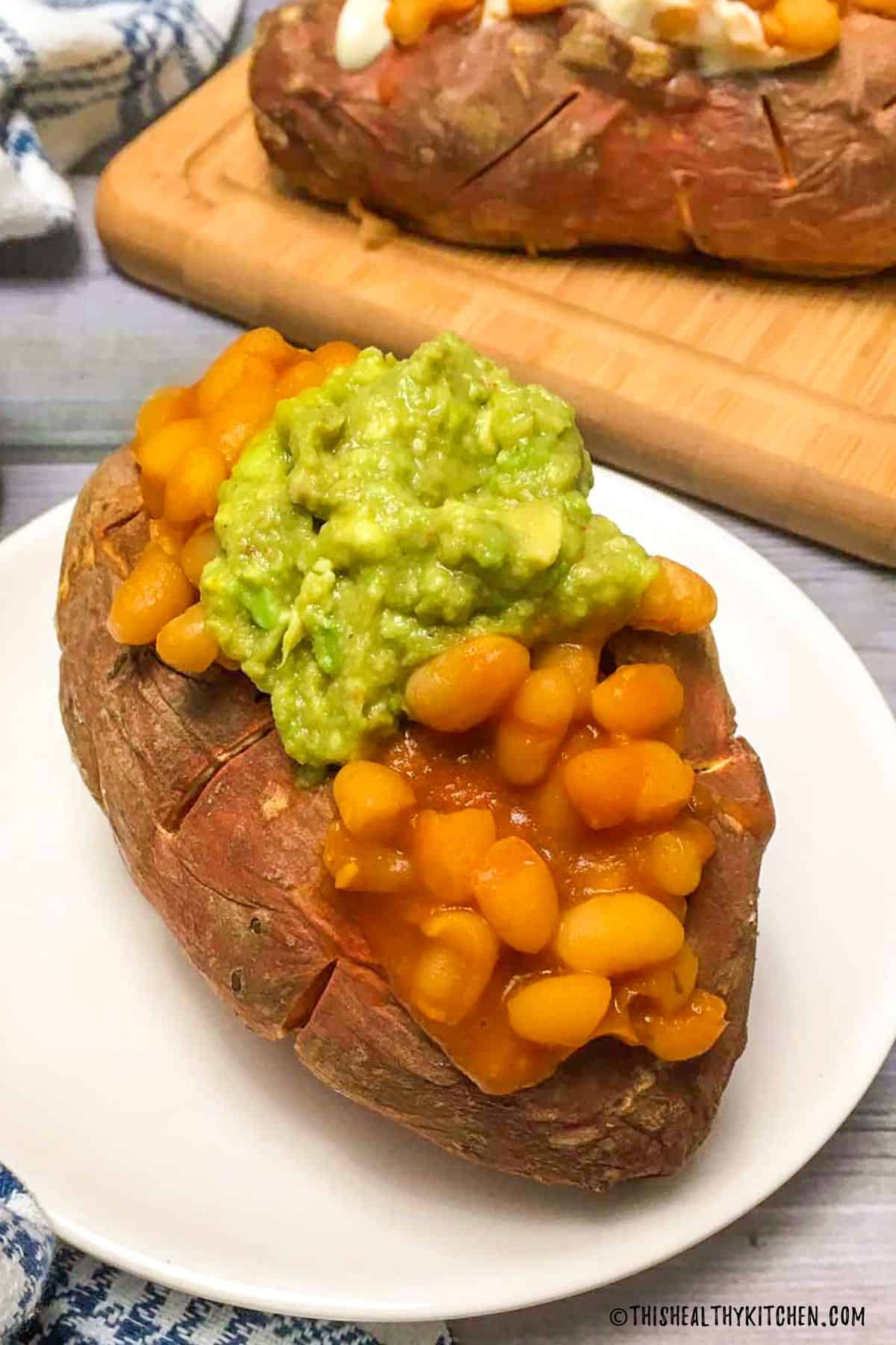 Baked sweet potato with baked beans and guacamole on top.