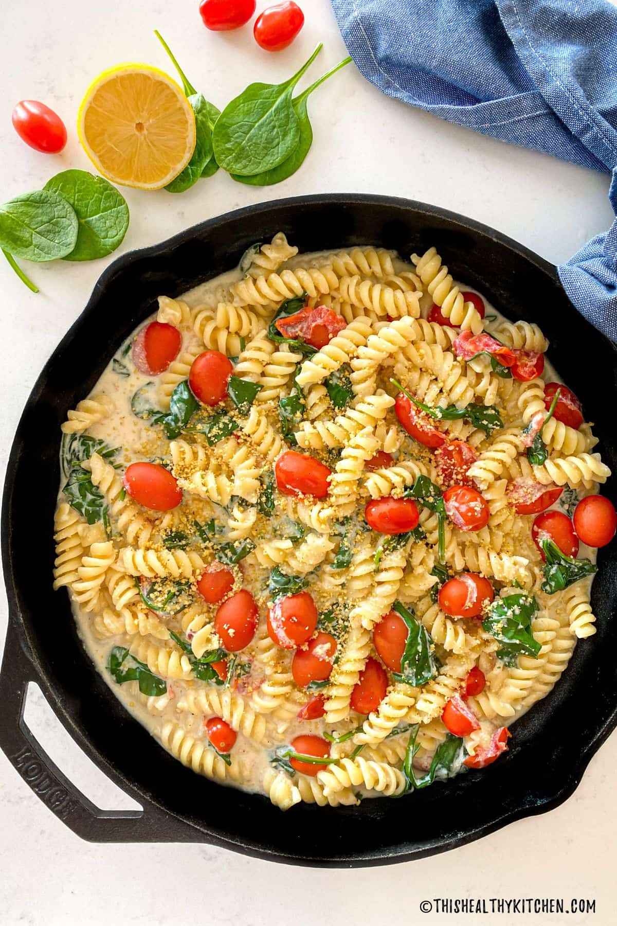 Tofu pasta sauce with rotini pasta, tomatoes and spinach in skillet.