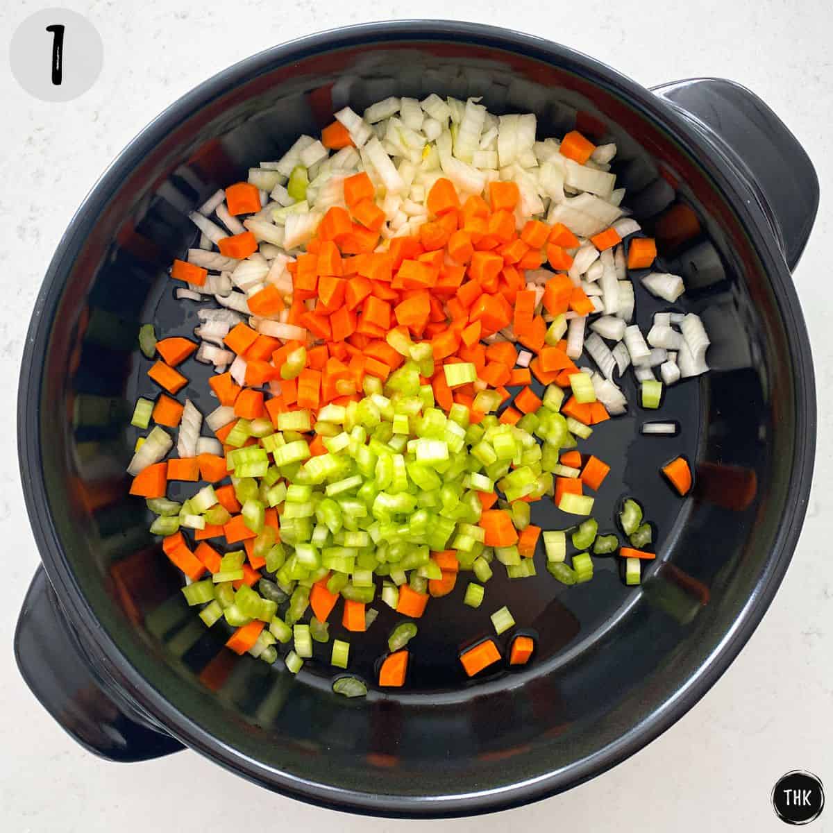 Deep pan with diced onion, carrots, and celery inside.