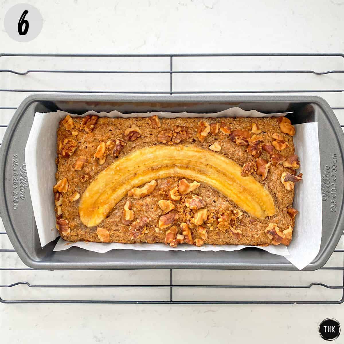Baked buckwheat banana bread in loaf pan on top of cooling rack.
