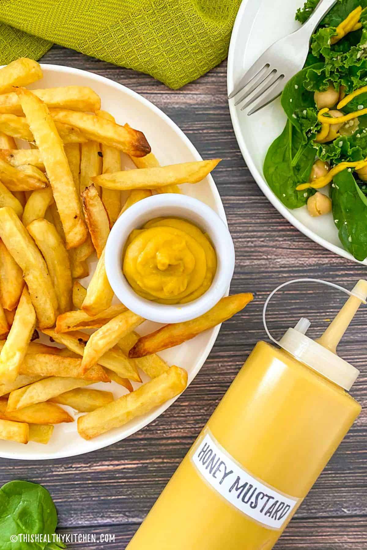 Plate of french fries with dipping bowl of vegan honey mustard.